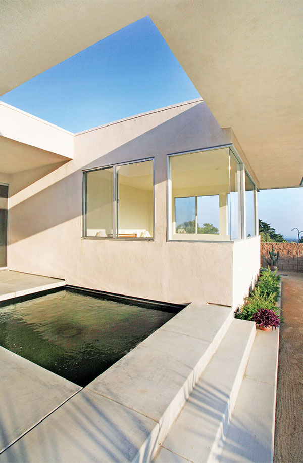 Remodeled Modern house with white stucco walls, large windows, and minimalist pond