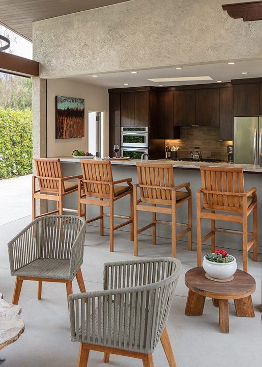 Kitchen space featuring wooden chairs, dark wood cabinetry, stainless steel appliances, and tan backsplash.