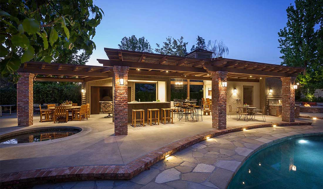 Perfect Summer Retreat by HartmanBaldwin - Hartman Baldwin Pre-Launch Exterior of a brick and wood patio with a pool. Outdoor seating, bar, pool, and hot tub.