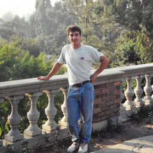 Reg Abersek standing by stone fence.