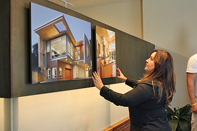 Woman hanging examples of HartmanBaldwin's work on a wall.