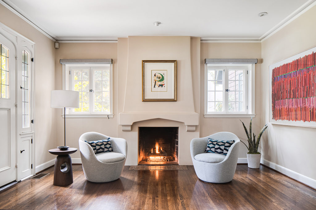 Living room view from an English cottage interior design remodel showcasing two armchairs in front of a fireplace