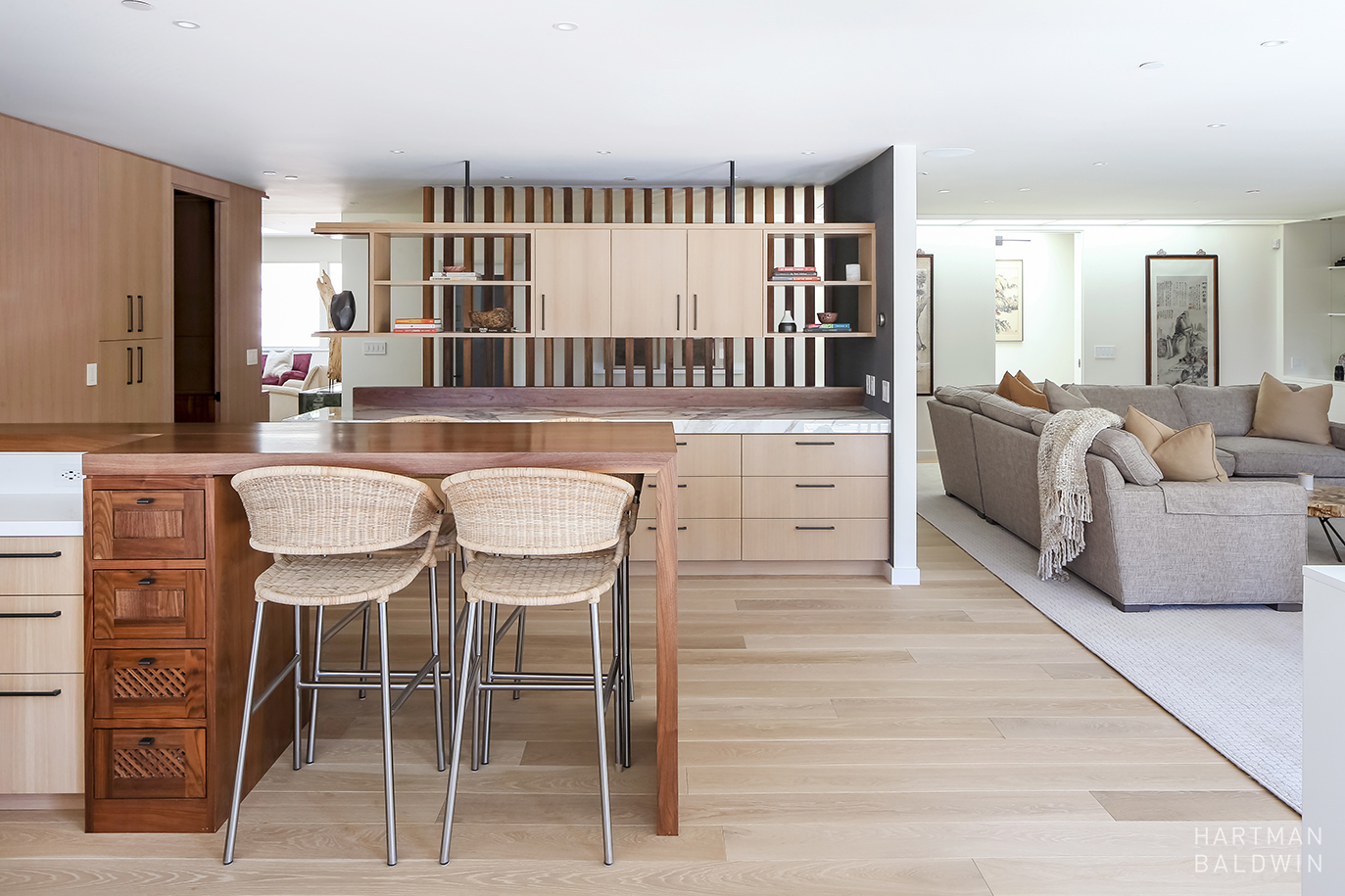 Stylish kitchen with fine wood cabinets and island and a living room with grey couch.
