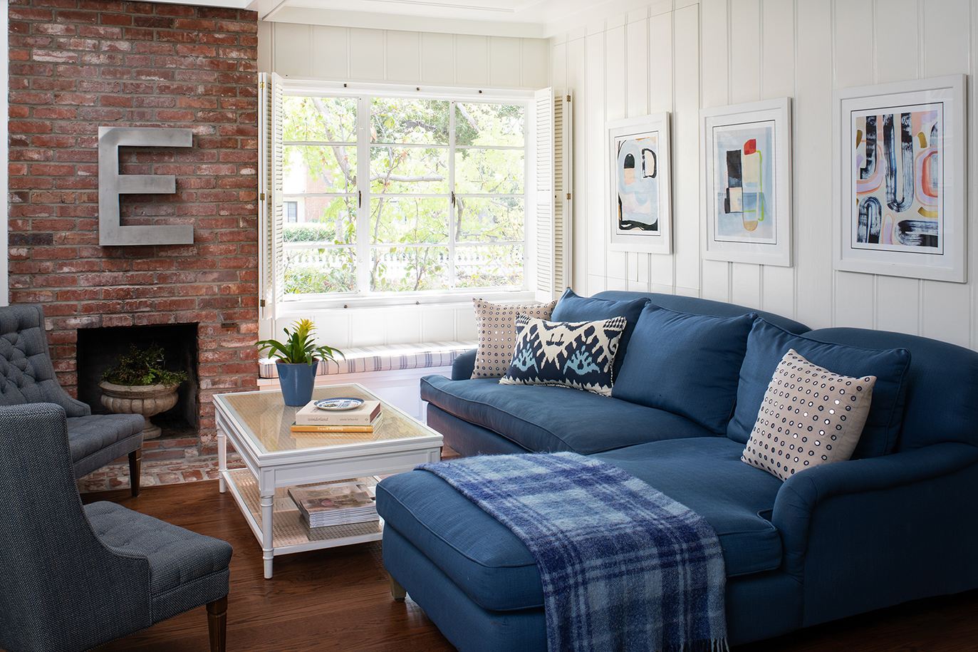 Living room remodel with a red brick fireplace, window seat, and large blue couch