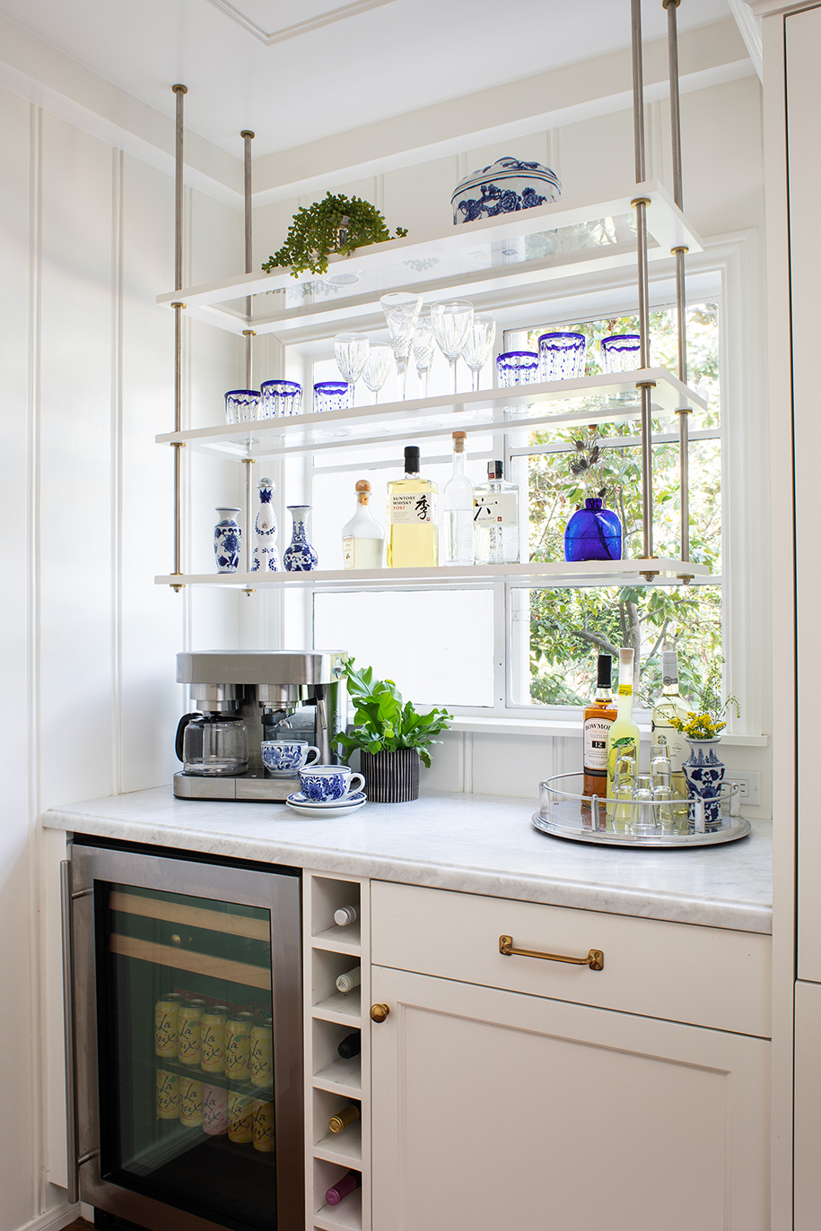Remodeled kitchen coffee and bar nook with floating glass shelves, espresso machine, wine bottle shelves, and mini beverage fridge