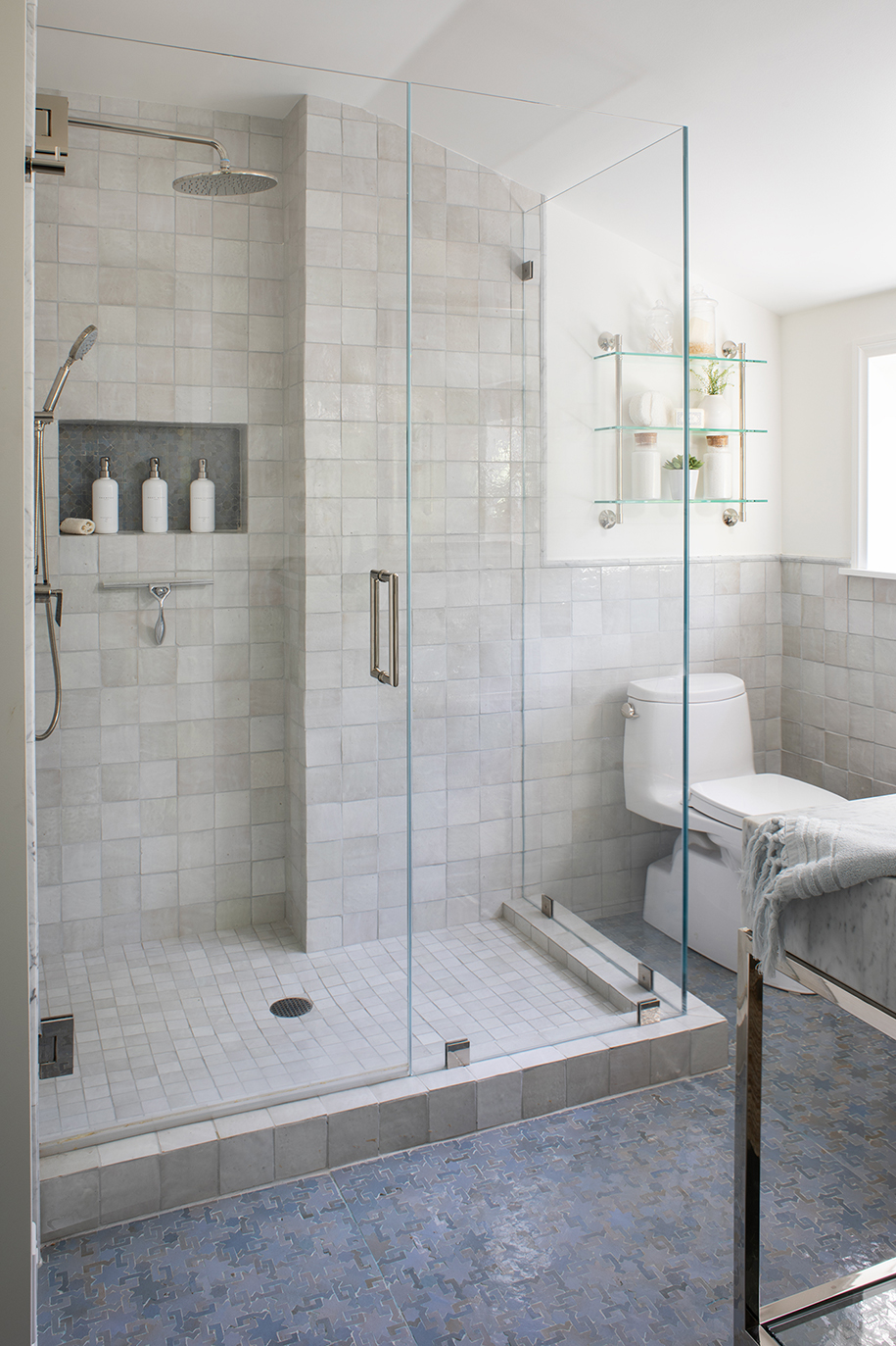 Serene master bathroom with blue Moroccan mosaic tile and light grey Zellige tile shower with glass walls