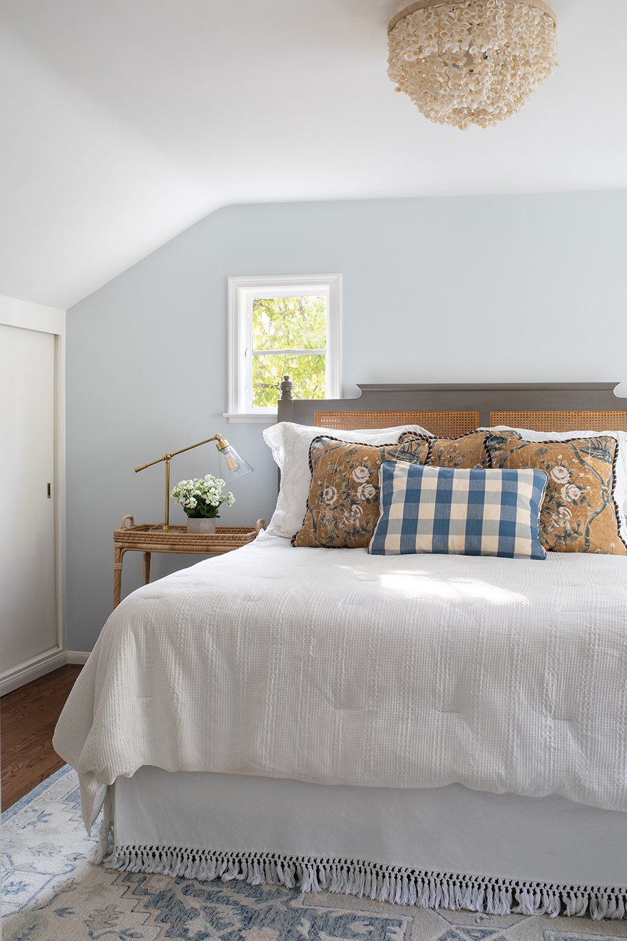 Beachy master bedroom with seafoam blue wall, shell chandelier, and white linen bedding