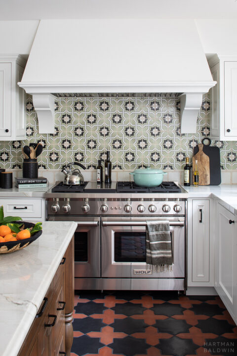Spanish Style Kitchen Remodel in Southern California with Wolf range, white plaster hood, and green glazed Casablanca ceramic tile backsplash
