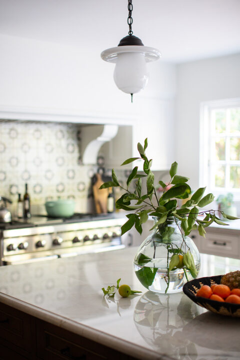 Lemon branches in glass vase with Spanish-style kitchen in background