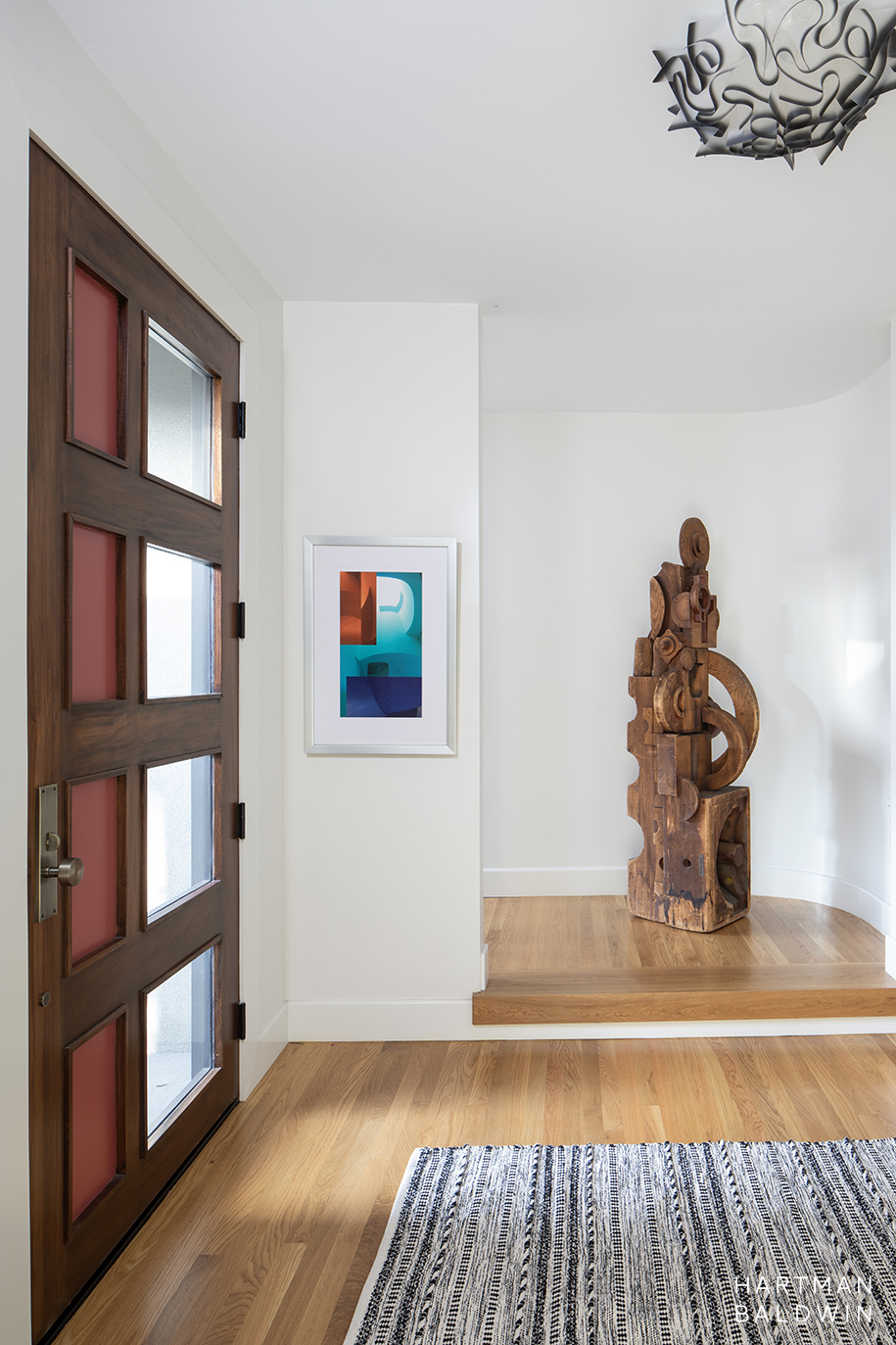 Mid-Century Modern foyer with artistic paneled front door and abstract wooden sculpture