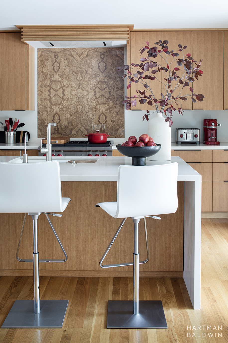 Mid-Century Modern kitchen renovation with waterfall-edge central island, oak slab-style cabinetry, and book-matched wood veneer backsplash