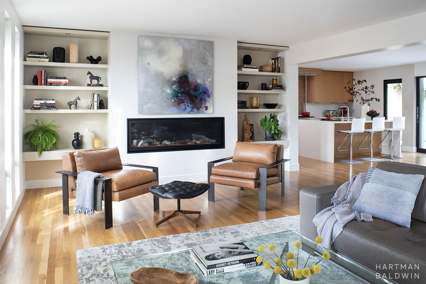 Mid-Century Modern open concept living space and kitchen with sleek fireplace, built-in open shelving, waterfall edge kitchen island, and oak kitchen cabinetry