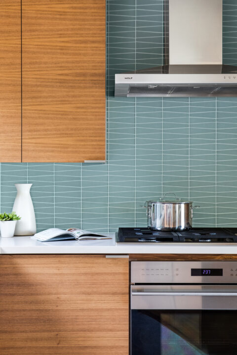 Kitchen remodel featuring stainless steel appliances, wood cabinetry, and teal tile backsplash.