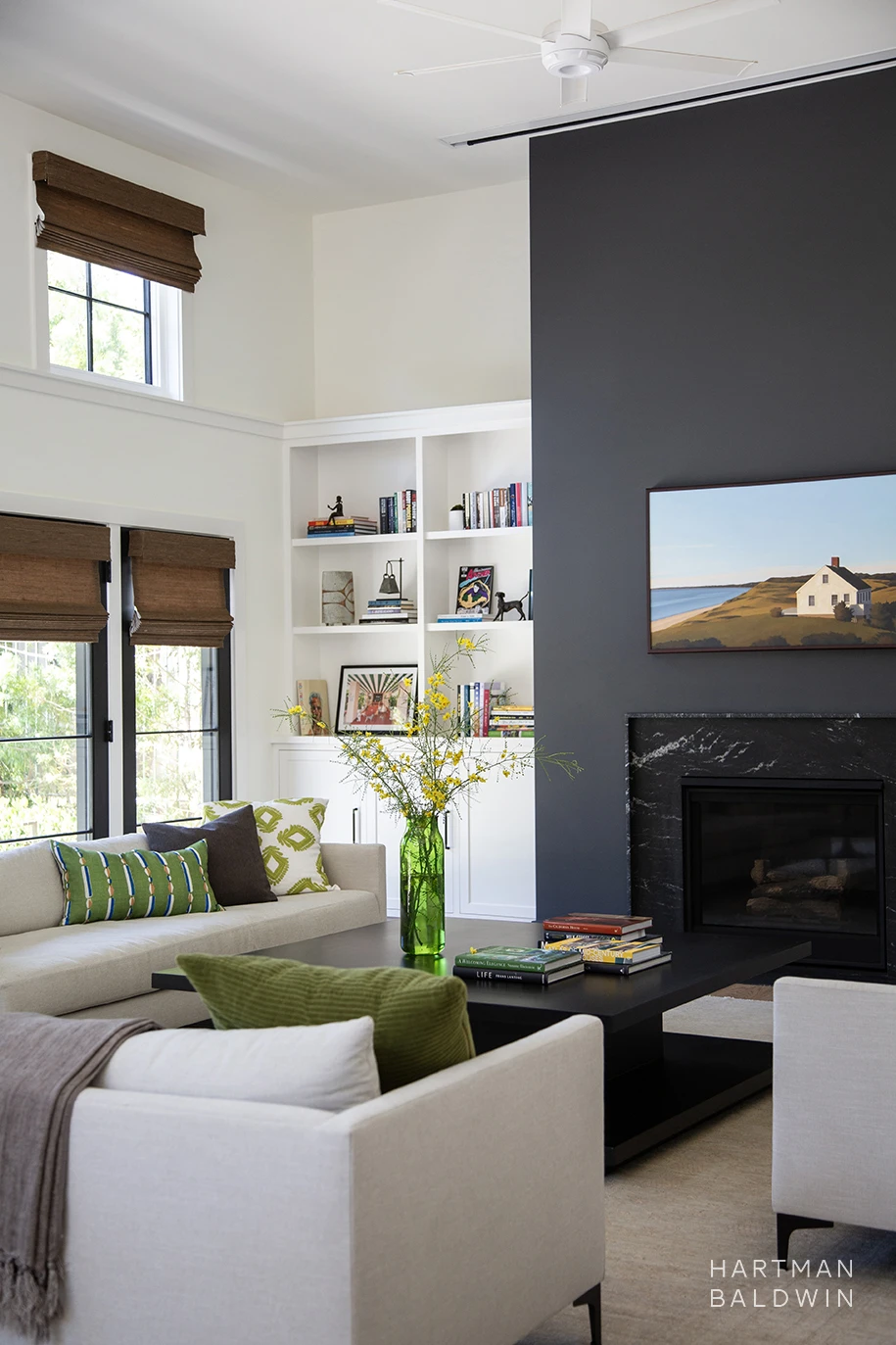 Great room with built-in bookshelves, comfortable contemporary couches, and floor-to-ceiling navy blue and black stone fireplace