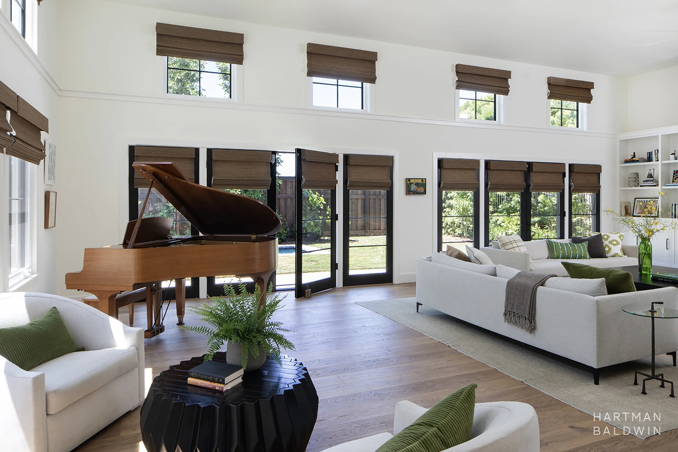 Great room with grand piano, French doors, built-in shelving, and comfortable seating inside new custom-built Los Angeles home
