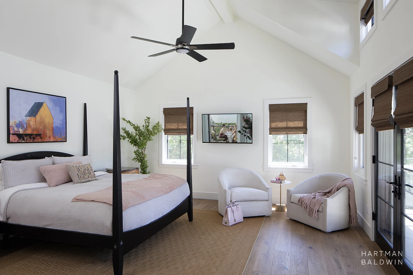 New custom primary bedroom with a vaulted ceiling, French doors leading to a balcony, and soft pink accessories