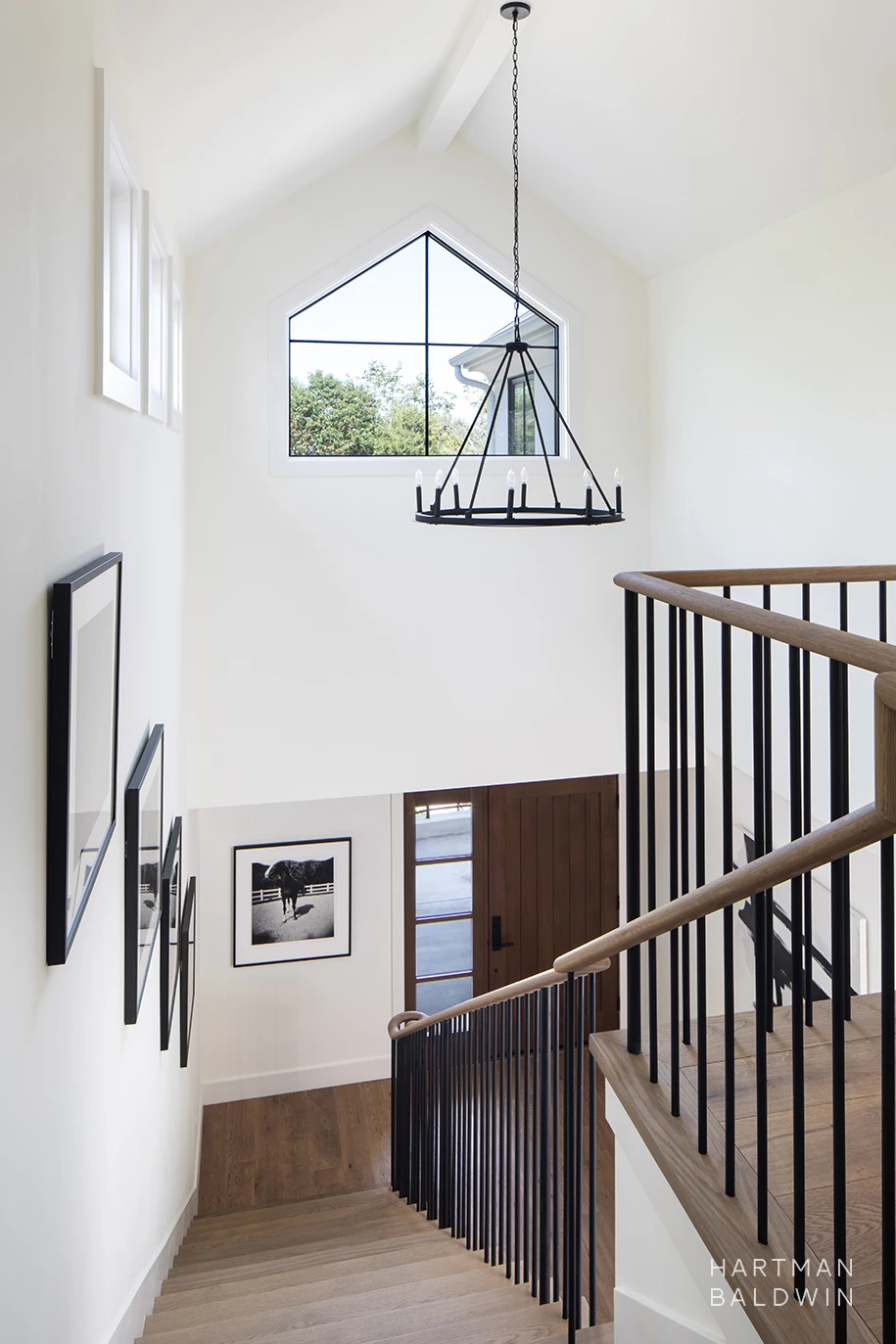 Entryway staircase with vaulted ceiling, large window, and modern minimalist chandelier