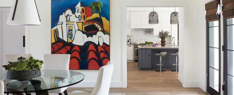 New custom modern dining room with a large colorful painting on the wall and the kitchen with white and blue cabinetry seen beyond