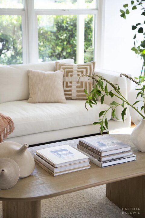 HartmanBaldwin Berlyn Residence Contemporary Living Room Coffee Tale - Hartman Baldwin Pre-Launch Bright and contemporary remodeled living room with white couch, neutral pillows, and wooden coffee table with interior design photo books, wood accessories, and foliage in white vase