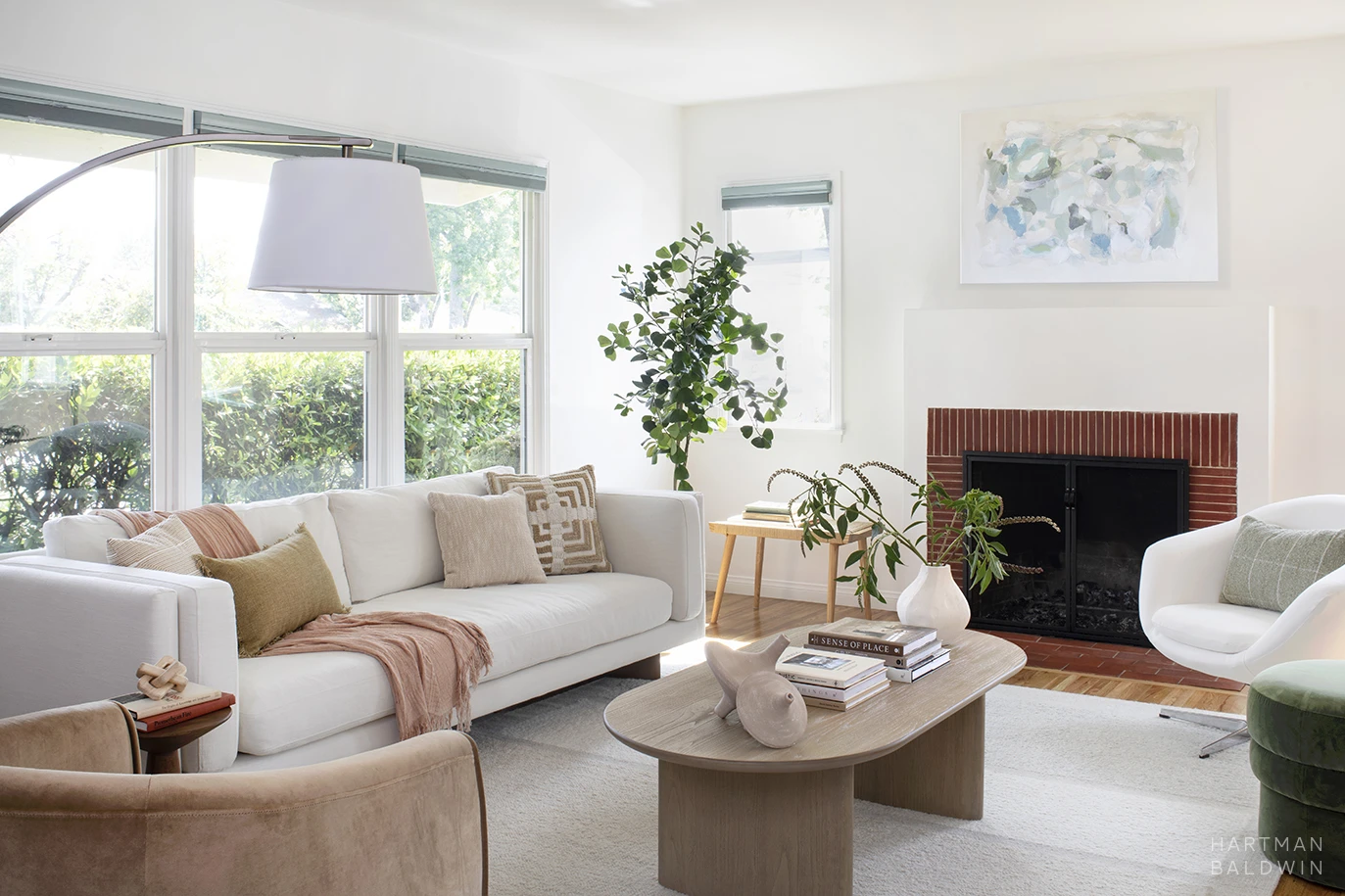 Bright, contemporary living room remodel with light, neutral furnishings and accessories and a red brick fireplace