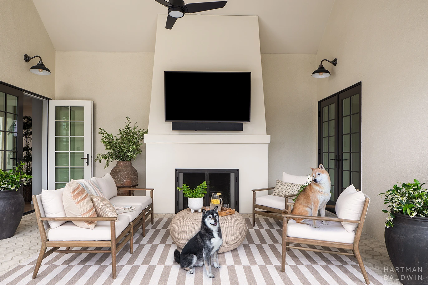 HartmanBaldwin Cambridge Residence California Room California room patio with fireplace, TV, and patio furniture with two Shiba Inu dogs