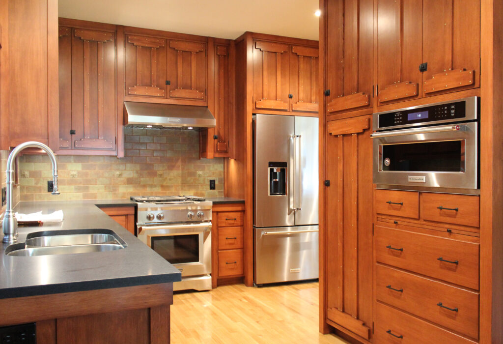 HartmanBaldwin Canyon Residence Craftsman Remodel Kitchen - Hartman Baldwin Pre-Launch Remodeled Craftsman-inspired kitchen with stained wood cabinetry, stainless steel appliances, dark stone countertops, and green backsplash tiles