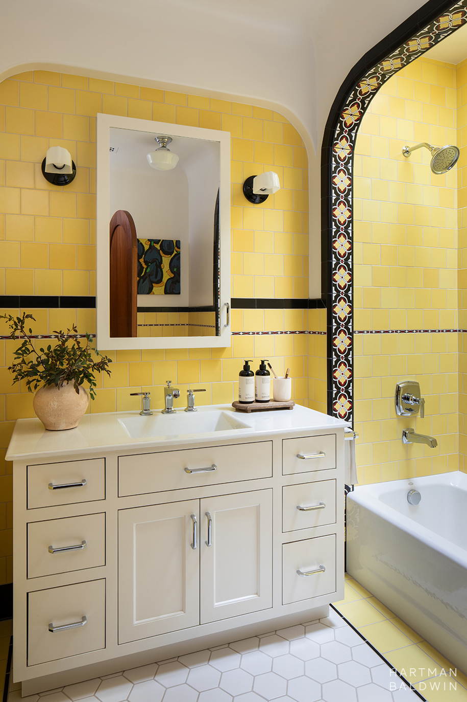 Spanish-style bathroom with vibrant yellow floor-to-ceiling wall tiles, patterned accent tiles, and white vanity