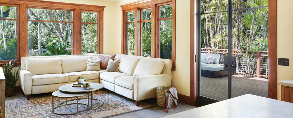 Craftsman-style living room with large wood-trim windows and French doors leading to outdoor deck