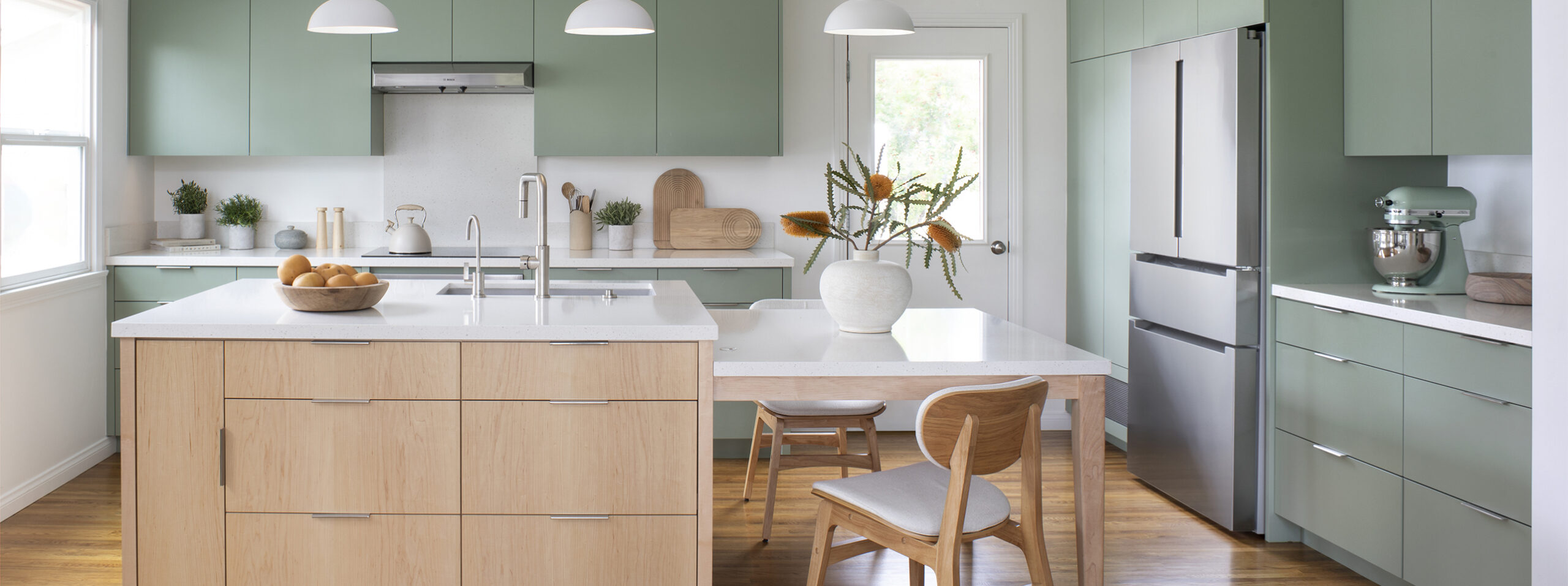 HartmanBaldwin Berlyn Residence Scandinavian Kitchen Remodel Cover - Hartman Baldwin Pre-Launch Contemporary Scandinavian minimalist style kitchen remodel with sage green cabinetry, sculptural pendant lights, and central island with built-in dining table