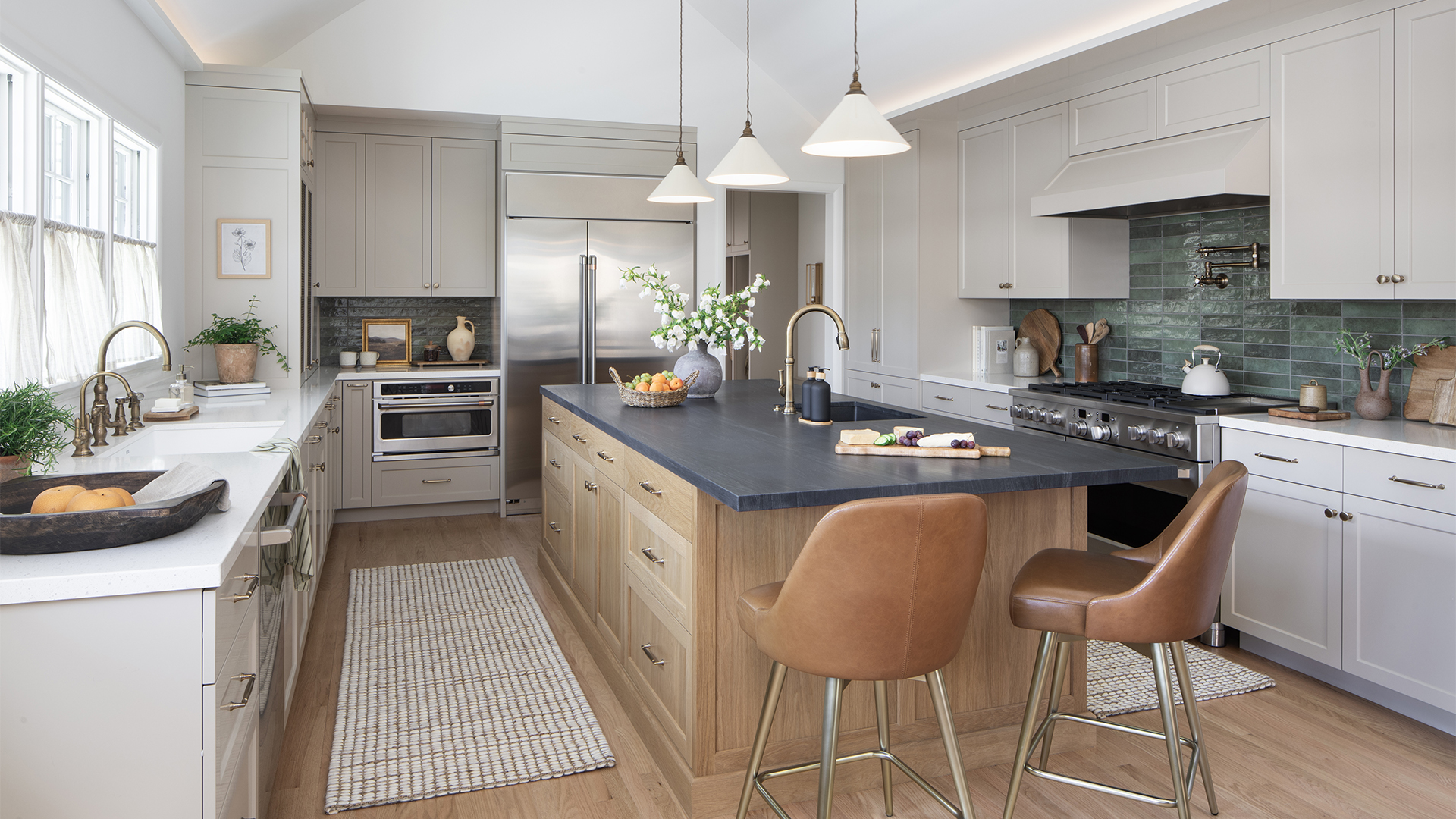 Contemporary kitchen remodel with wood and dark stone island, tan perimeter cabinetry, dark turquoise tile backsplash, and vaulted ceiling with cove lighting