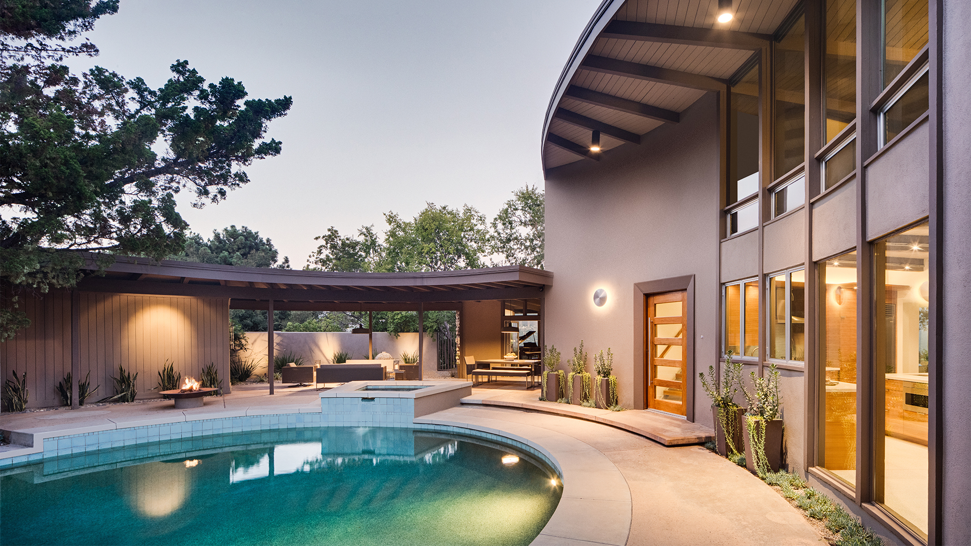 Unique circular Mid-Century Modern home, pool, and patio at dusk