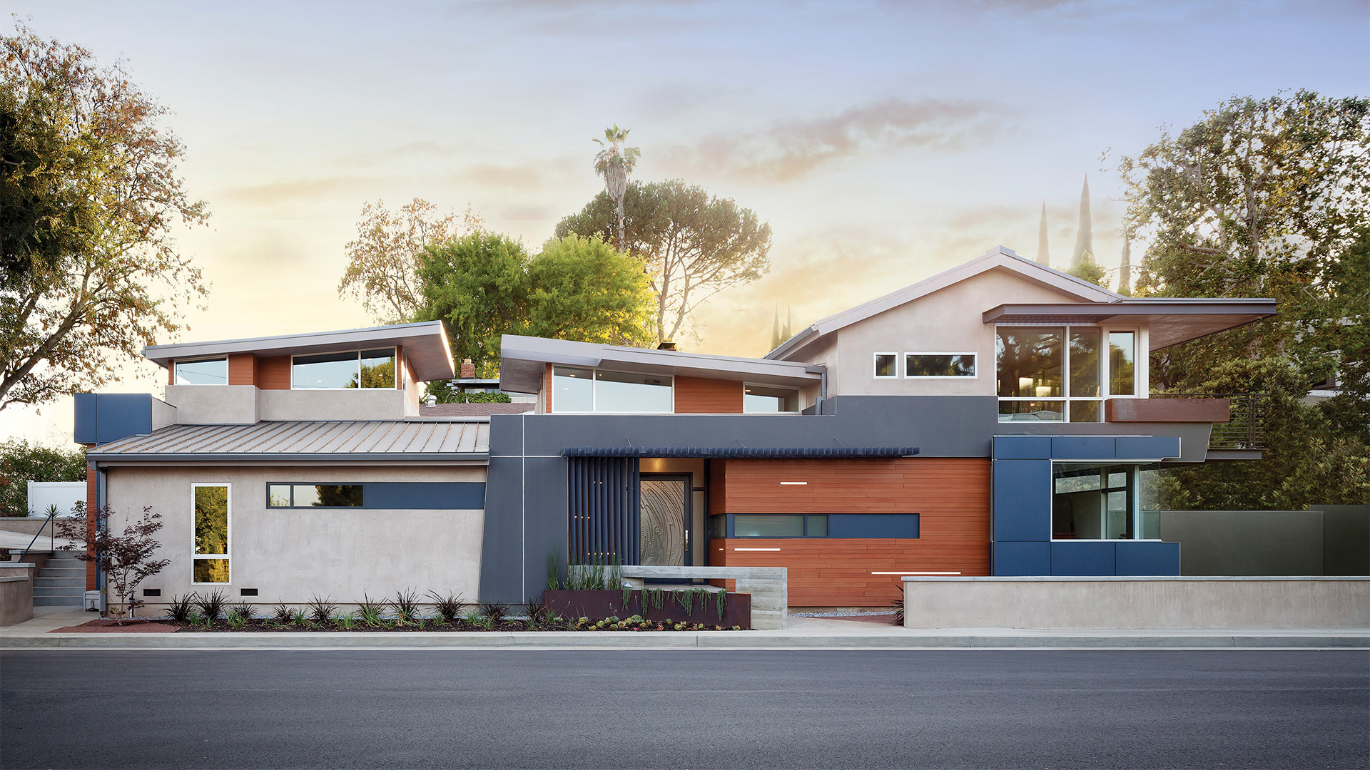 Modern home remodel at sunset with geometric motifs, orange and blue color blocks, and strip light accents